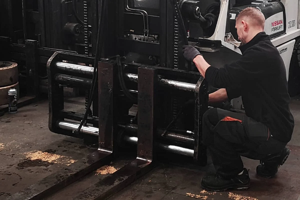 un technicien sav vdm technologies effectue l'installation de flexibles et raccords hydrauliques sur un chariot elevateur