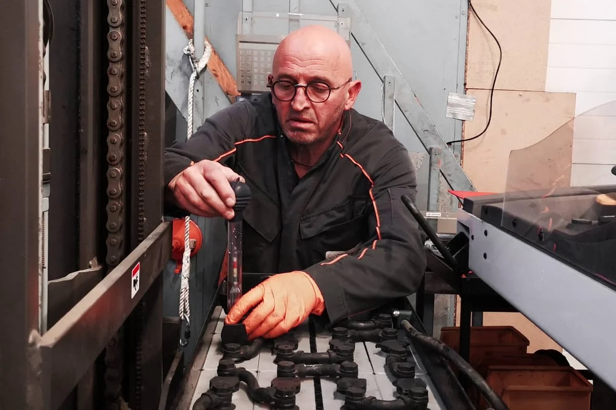 technicien atelier effectue une regeneration de batterie sur un chariot elevateur
